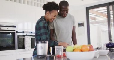 Video of happy african american couple preparing meal together in kitchen. Love, relationship and spending quality time together concept.