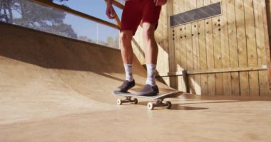 Video of low section of caucasian male skateboarder training in skate park. Skateboarding, sport, active lifestyle and hobby concept.