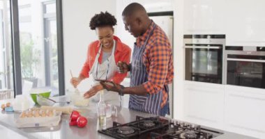 Video of happy african american couple baking together with tablet. Love, relationship and spending quality time together concept.