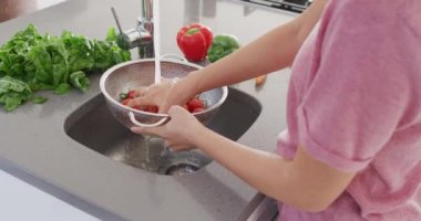 Video of midsection of asian woman washing vegetables. Lifestyle and spending time at home concept.