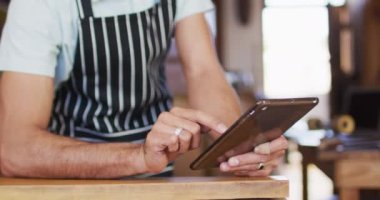 Video of middle eastern male seller using tablet in coffee shop. Cafe, running small business concept.