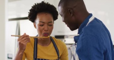 Video of happy african american couple cooking together, trying dish. Love, relationship and spending quality time together concept.