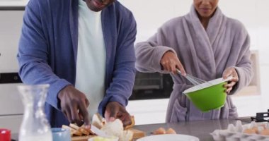 Video of happy african american couple preparing breakfast together in kitchen. Love, relationship and spending quality time together concept.