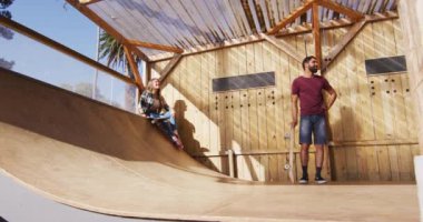 Video of happy diverse female and male skateboarders training in skate park. Skateboarding, sport, active lifestyle and hobby concept.