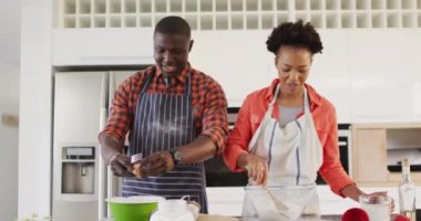 Video of happy african american couple baking together in kitchen. Love, relationship and spending quality time together concept.