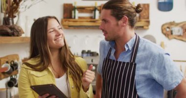 Video of happy caucasian male seller in coffee shop and female owner with tablet. Cafe, running small business concept.