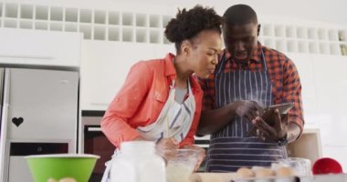 Video of happy african american couple baking together in kitchen. Love, relationship and spending quality time together concept.