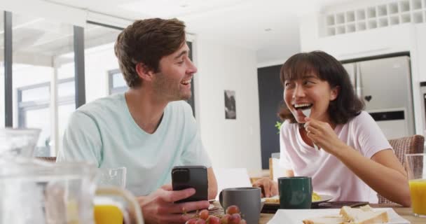 Video Happy Diverse Couple Using Smartphone Drinking Coffee Together Kitchen — Stock video