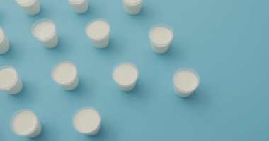 Video of row of glasses of milk on blue background. dairy products and healthy organic nutrition.