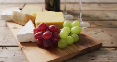 Video of cheeses and grapes on board wine bottle and glasses on wooden table, with copy space. quality light food snack and drink.