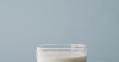 Video of glass of milk with copy space on blue background. dairy products and healthy organic nutrition.