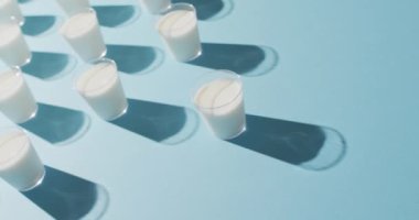 Video of row of glasses of milk on blue background. dairy products and healthy organic nutrition.