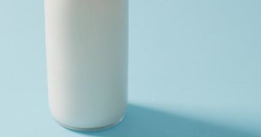 Video of glass bottle of milk on blue background. dairy products and healthy organic nutrition.