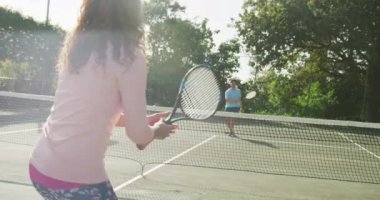 Video of happy biracial couple playing tennis on the court. Healthy active lifestyle and fitness at home.