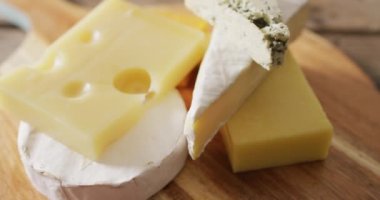 Video close up of assorted hard and soft cheeses on wooden chopping board. quality, tasty light food snack.