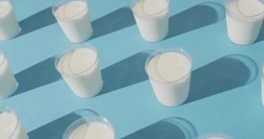 Video of row of glasses of milk on blue background. dairy products and healthy organic nutrition.