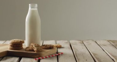Video of glass bottles of milk and cookies on wooden table on white background. dairy products and healthy organic nutrition.