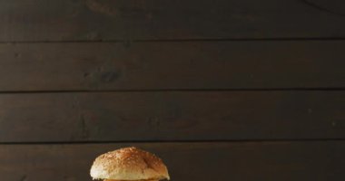 Video of cheeseburger and chips against rustic wooden background with copy space. tasty hot homemade fast food meal.