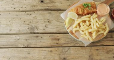 Video of fish and chips on wooden board with dips, with copy space on wooden table. tasty hot fast food meal.