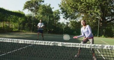 Video of happy caucasian couple playing tennis on the court. Healthy active lifestyle and fitness at home.
