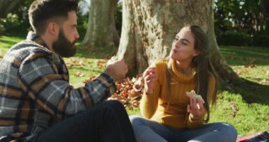 Video of happy caucasian warmly dressed couple eating in the garden. Domestic lifestyle and leisure time in the garden.