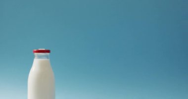 Video of glass bottle of milk on blue background. dairy products and healthy organic nutrition.