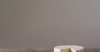 Video close up of soft cheeses and knife on wooden chopping board, with copy space. quality, tasty light food snack.