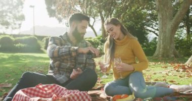 Video of happy caucasian warmly dressed couple drinking wine in the garden. Domestic lifestyle and leisure time in the garden.