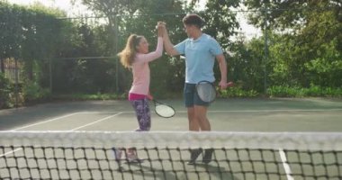 Video of happy biracial couple playing tennis on the court. Healthy active lifestyle and fitness at home.