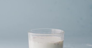 Video of glass of milk with copy space on blue background. dairy products and healthy organic nutrition.