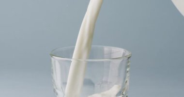 Video of glass of milk with copy space on blue background. dairy products and healthy organic nutrition.