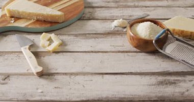 Video of parmesan cheese and grated parmesan in bowl with grater on rustic table with copy space. savoury cooking ingredient and food preparation.