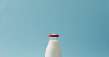 Video of glass bottle of milk on blue background. dairy products and healthy organic nutrition.
