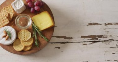 Video of cheese, biscuits, grapes and rosemary on wooden board and rustic table top with copy space. quality, tasty light food snack.