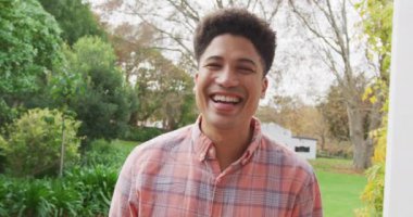 Video of biracial smiling man in the garden. Domestic lifestyle and leisure time at home.