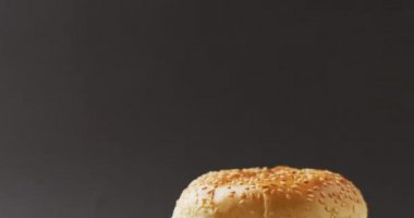 Video of cheeseburger with salad in burger bun, on grey background with copy space. tasty hot homemade fast food meal.