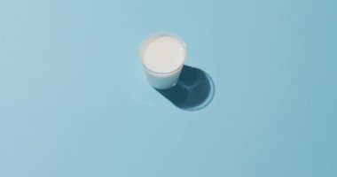 Video of glass of fresh milk over blue background. dairy products and healthy organic nutrition.