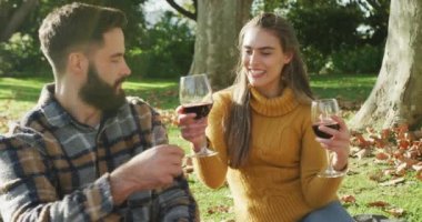 Video of happy caucasian warmly dressed couple drinking wine in the garden. Domestic lifestyle and leisure time in the garden.