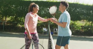 Video of happy biracial couple playing tennis on the court. Healthy active lifestyle and fitness at home.