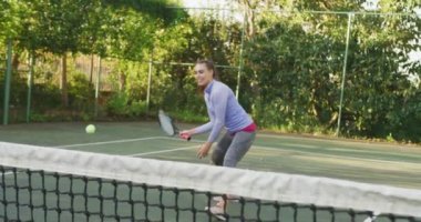 Video of happy caucasian woman playing tennis on the court. Healthy active lifestyle and fitness at home.