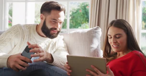 Video Happy Caucasian Couple Siting Sofa Using Tablet Smartphone Domestic — Video Stock