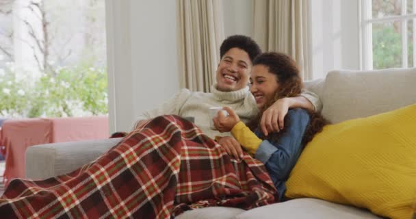 Video Happy Biracial Couple Siting Sofa Blanket Drinking Coffee Domestic — Stockvideo