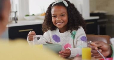 Afro-Amerikalı mutlu bir kızın yemek masasında ailesiyle gülüp yemek yediği bir video. Aile, aile hayatı ve birliktelik kavramı dijital olarak oluşturulmuş video.