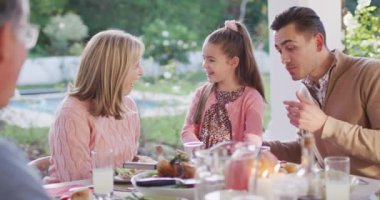 Video of happy caucasian father, daughter and grandparents talking at outdoor dinner table. Family, domestic life and togetherness concept digitally generated video.