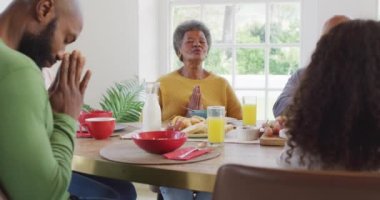 Afro-Amerikan ailelerin, kız çocuklarının ve büyükbabalarının yemek masasında dua ettikleri videolar. Aile, aile hayatı ve birliktelik kavramı dijital olarak oluşturulmuş video.