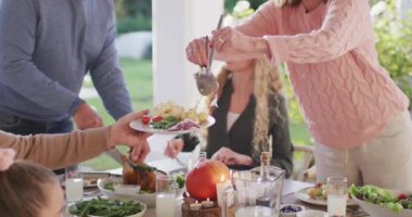 Video of happy caucasian parents, daughter and grandparents serving food at outdoor table. Family, domestic life and togetherness concept digitally generated video.