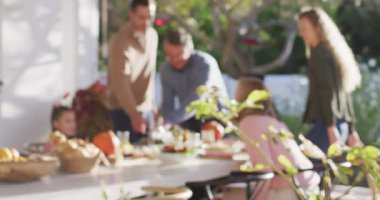 Video of happy caucasian parents, daughter and grandparents sitting at outdoor table for family meal. Family, domestic life and togetherness concept digitally generated video.