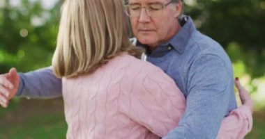 Video of happy caucasian senior husband and wife hugging in garden. Family, love and togetherness concept digitally generated video.