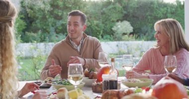 Video of happy caucasian father telling story at outdoor family dinner table. Family, domestic life and togetherness concept digitally generated video.