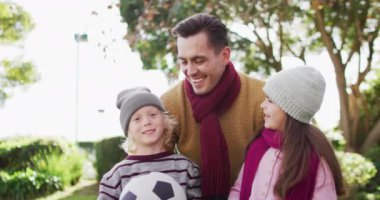 Video portrait of happy caucasian father smiling with son and daughter in autumn garden. Family, domestic life and togetherness concept digitally generated video.